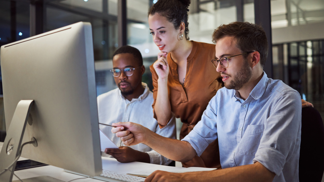 Team, office and computer workshop for planning, strategy or goal for marketing business in overtime. Collaboration, teamwork and meeting at desk for creative vision, innovation or idea at work